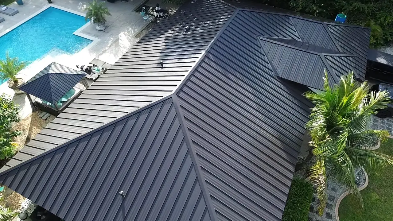Aerial view of a dark metal roof installed by Tropico Roofing, showing panel seams, ridges and valleys