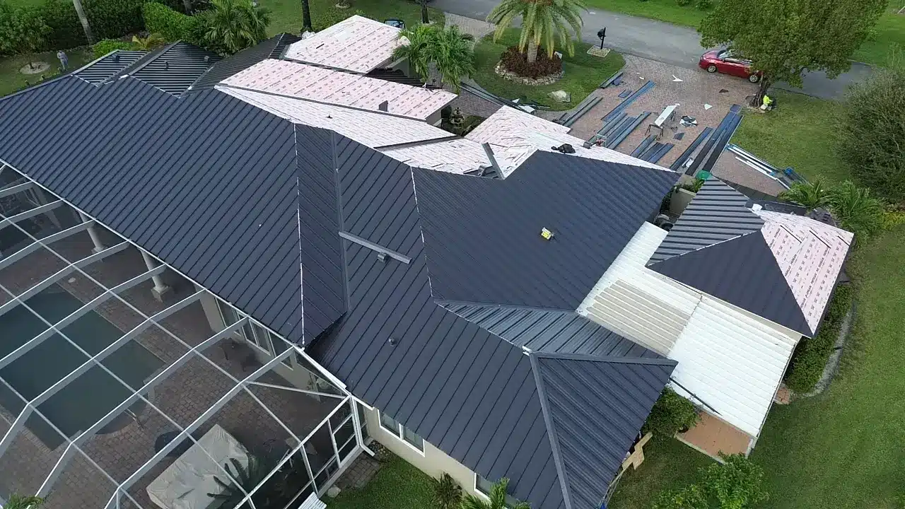 Aerial view of a Tropico Roofing metal roof installation with finished panels beside exposed underlayment
